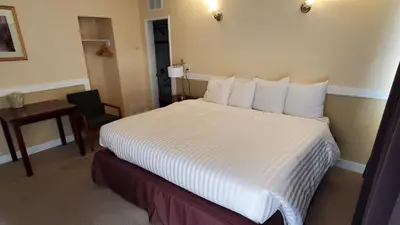 a hotel room with a large bed and a chair at Comox Valley Inn & Suites in Courtenay