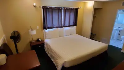 a bedroom with a white bed with a window and a desk at Comox Valley Inn & Suites in Courtenay