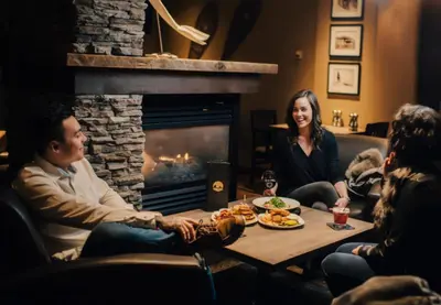 a group of people sitting around a table in front of a fireplace at The Explorer Hotel in Yellowknife