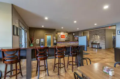 a kitchen with a bar with stools in a room at Devonian Hotel and Suites in Fox Creek