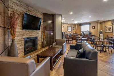 a lobby with couches and a fireplace and a restaurant at Devonian Hotel and Suites in Fox Creek