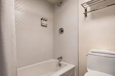 a white bathroom with a toilet and a bath tub at Holiday Inn & Suites Vancouver Downtown by IHG in Vancouver