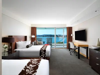 a hotel room with two beds and a desk and a television at Inn at Laurel Point in Victoria