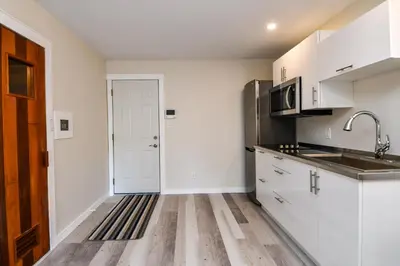 a kitchen with white cabinets and a sink and a door at Chateau Riverside in Campbell River