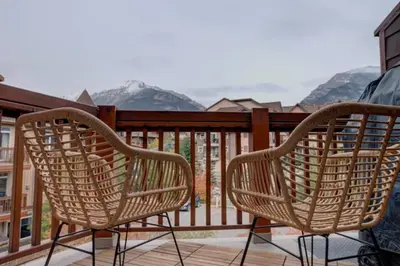 two wicker chairs sitting on a balcony with mountains at ⭐️ Luxury Mountain View Studio in Canmore ⭐️ in Canmore