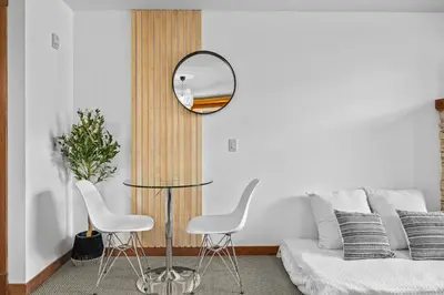a living room with two white chairs and a mirror at ⭐️ Luxury Mountain View Studio in Canmore ⭐️ in Canmore