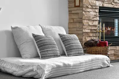 a couch with four pillows in front of a fireplace at ⭐️ Luxury Mountain View Studio in Canmore ⭐️ in Canmore