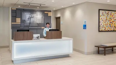 a woman standing behind a counter in a hospital lobby at Holiday Inn Express Airdrie by IHG in Airdrie