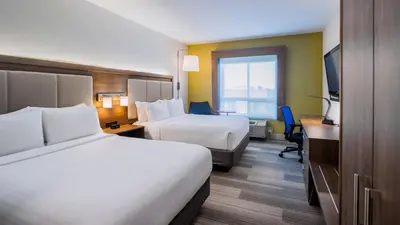 a hotel room with two beds and a desk at Holiday Inn Express Airdrie by IHG in Airdrie