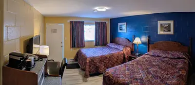 a hotel room with two beds and a television at Gold Pan Motel in Quesnel