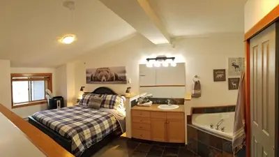 a bedroom with a bed and a sink and a tub at Downtown Loft, Mountain Views, Fireplace, Couple's Retreat, Walker's Paradise in Canmore