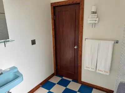 a bathroom with a wooden door and a sink and towels at Rodmay Hotel in Powell River