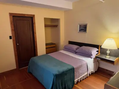 a bedroom with a bed with purple pillows and a lamp at Rodmay Hotel in Powell River