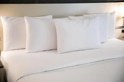 a white bed with white pillows on top of it at Days Inn by Wyndham Chetwynd in Chetwynd