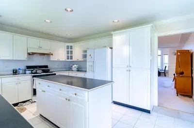 a kitchen with white cabinets and a black counter top at 3 Private, spacious, bright rooms in a Gorgeous house in New Westminster