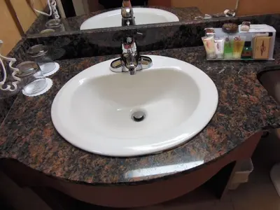 a bathroom counter with a white sink in it at Rosslyn Inn & Suites in Edmonton