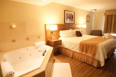 a hotel room with a bed and a bath tub at Rosslyn Inn & Suites in Edmonton
