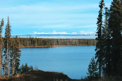 a large blue lake with snow capped mountains in the background at Red Cariboo Apartments in Anahim Lake