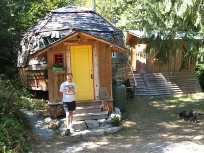 a boy standing in front of a cabin with a yellow door at The Magical Dome in Lund