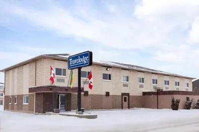 a sign in front of a building with flags at Travelodge by Wyndham Meadow Lake in Meadow Lake