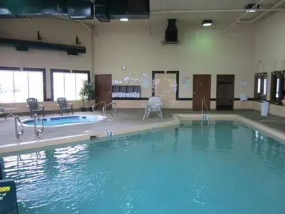 a large pool of water in a gym with chairs at Super 8 by Wyndham Fort St. John BC in Fort Saint John