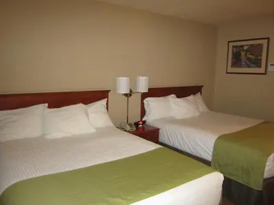 a hotel room with two beds with green and white sheets at Super 8 by Wyndham Fort St. John BC in Fort Saint John