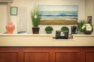 a reception desk with potted plants and a painting at Continental Inn & Suites in Edmonton