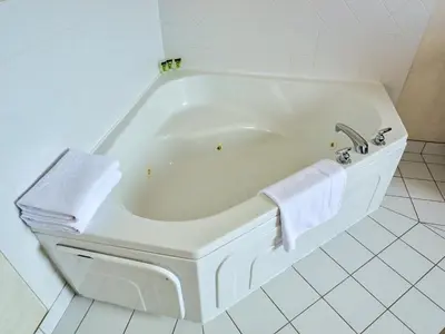 a white bath tub in a white tiled bathroom at Continental Inn & Suites in Edmonton
