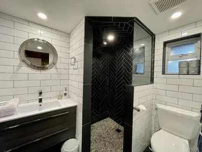 a bathroom with a toilet and a sink and a mirror at Waterfront Hot Tub Firepit King Bed - 6H in Ucluelet