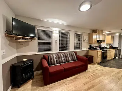a living room with a red couch and a flat screen tv at Cozy 2 Bedroom Waterfront Cottage With Hot Tub! in Ucluelet