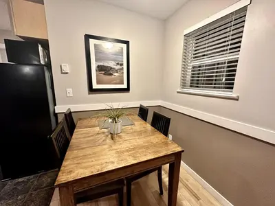 a dining room with a wooden table and a window at Cozy 2 Bedroom Waterfront Cottage With Hot Tub! in Ucluelet