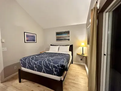 a bedroom with a bed with a blue comforter at Cozy 2 Bedroom Waterfront Cottage With Hot Tub! in Ucluelet