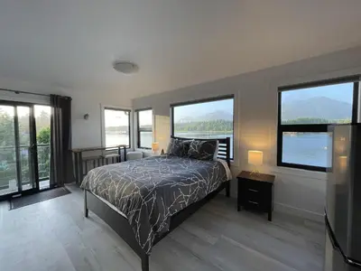 a bedroom with a bed and large windows at Oceanfront Room With Hot Tub & Firepit in Ucluelet