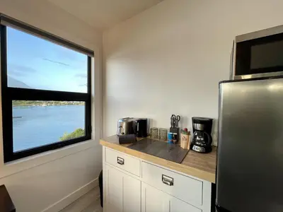 a kitchen with a refrigerator and a large window at Oceanfront Room With Hot Tub & Firepit in Ucluelet