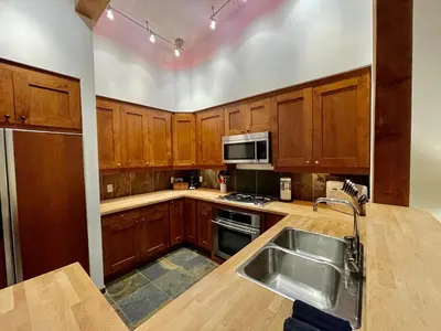 a kitchen with wooden cabinets and a stainless steel sink at Top-Floor Villa With Pacific Ocean Views Bbv in Ucluelet