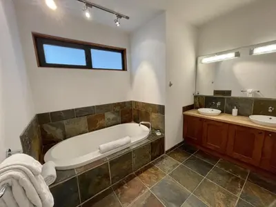 a bathroom with a tub and a sink and a mirror at Top-Floor Villa With Pacific Ocean Views Bbv in Ucluelet
