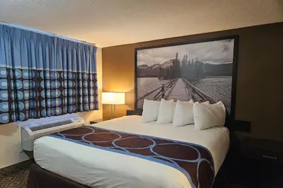 a hotel room with a large bed with a painting on the wall at Super 8 by Wyndham Spruce Grove in Spruce Grove