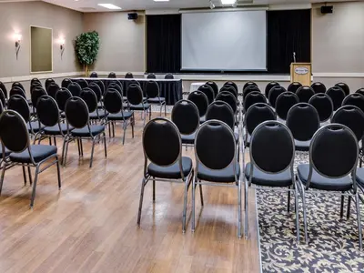 a conference room with black chairs and a screen at Heritage Inn Hotel & Convention Centre - Cranbrook in Cranbrook