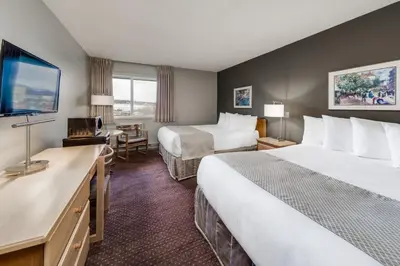 a hotel room with two beds and a flat screen tv at Heritage Inn Hotel & Convention Centre - Cranbrook in Cranbrook