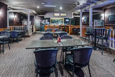a restaurant with tables and chairs and a bar at Heritage Inn Hotel & Convention Centre - High River in High River