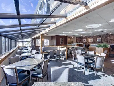 a restaurant with tables and chairs and windows at Heritage Inn Hotel & Convention Centre - High River in High River