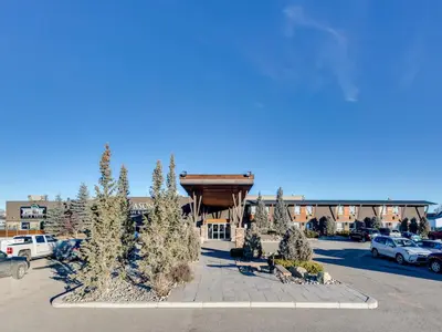 a hotel parking lot with trees and a building at Heritage Inn Hotel & Convention Centre - High River in High River