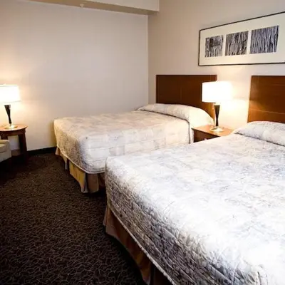 a hotel room with two beds and two lamps at Heritage Inn & Suites - Brooks in Brooks