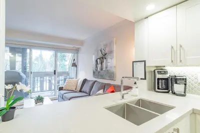 a kitchen with a sink and a living room at Sunpath by Outpost Whistler in Whistler