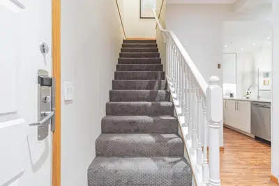 a staircase in a home with white walls and wood floors at Northstar by Outpost Whistler in Whistler