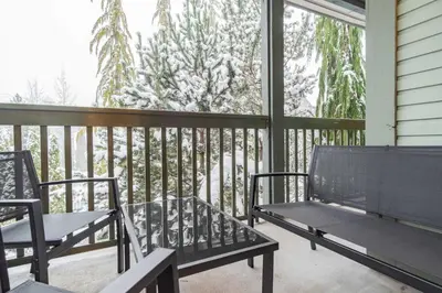two benches on a porch with snow covered trees at Northstar by Outpost Whistler in Whistler