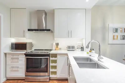 a white kitchen with white cabinets and a sink at Northstar by Outpost Whistler in Whistler