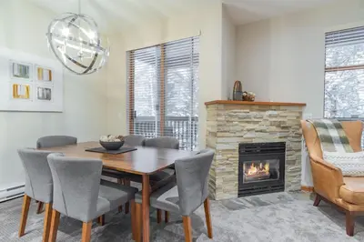 a dining room with a table and a fireplace at Northstar by Outpost Whistler in Whistler