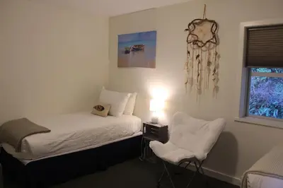 a bedroom with a bed and a chair and a window at Siennas Harbour House in Tofino