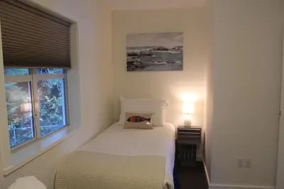 a white bedroom with a bed and a window at Siennas Harbour House in Tofino